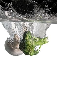 mushroom and broccoli thrown in water with black and white background