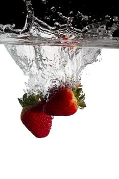 some strawberries thrown in water with black and white background
