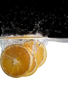 some orange slices thrown in water with black and white background