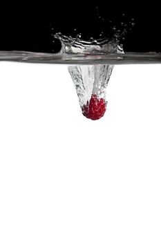 one red raspberry thrown in water with black and white background