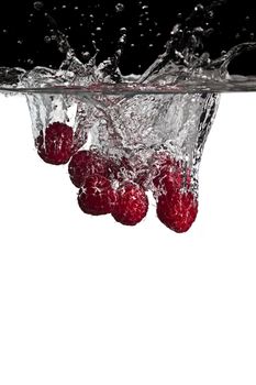 some raspberries thrown in water with black and white background