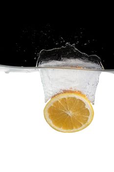 one slice of orange thrown in water with black and white background