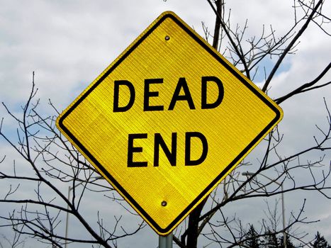 A dead end sign with a defoliated tree in the background lends an ominous tone
