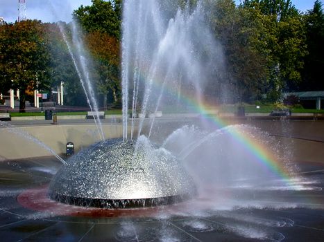 The fountain at Seattle center with a rainbow showing on the water display
