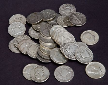 A pile of old silver coins on a black background
