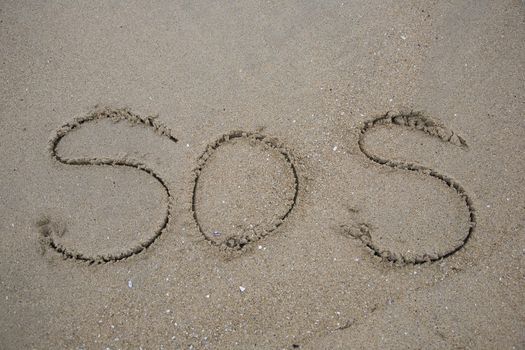 The term SOS for Save our Ship written in beach sand
