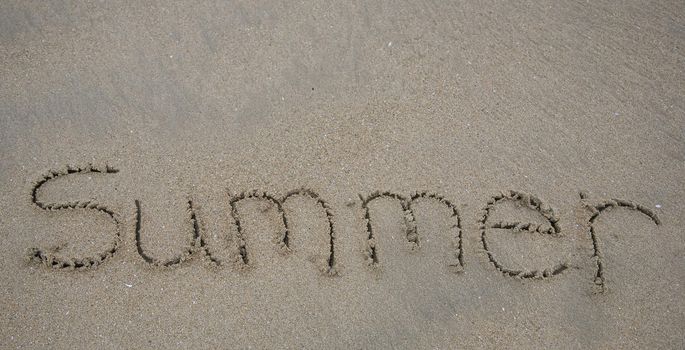 The word Summer written in beach sand
