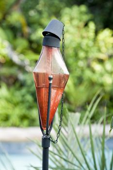 A shot of a red tiki torch almost ready for action in a tropical setting
