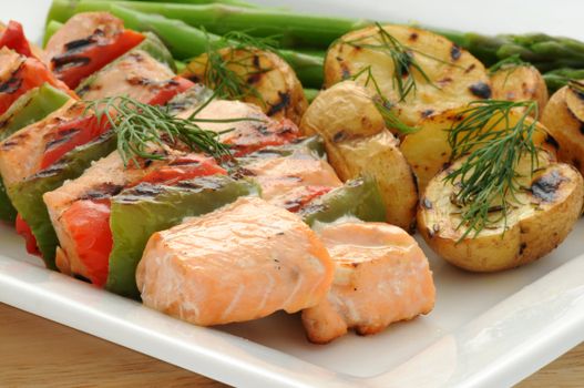 Grilled salmon kabobs served with vegetables and potato.