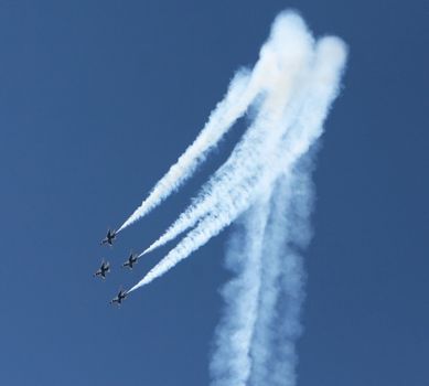 Four fighter jets flying in formation against a clear blue sky