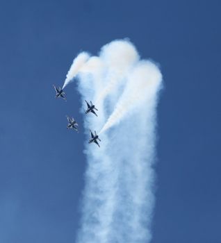 Four fighter jets flying in formation against a clear blue sky