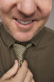 Smiling Man Fixing Tie Against Grey Background