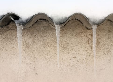 Three icicles hanging from roof