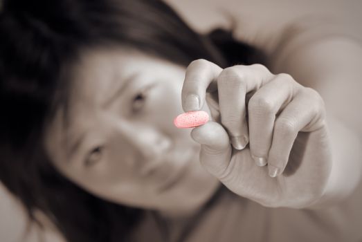 Sick woman holding pill with pain face.