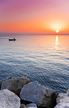 Man in a boat angling at sunset
