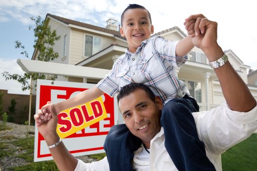 Hispanic Father and Son in Front of Their New Home with Sold Home For Sale Real Estate Sign. 