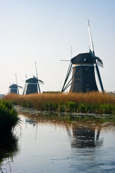 Dutch watermills at the waterside with reflection after sunrise