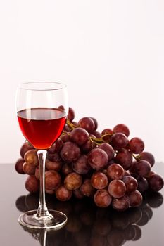 a glass of wine and red grapes