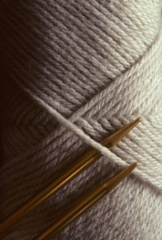 Two gold crocheting needles against a skein of wool yard