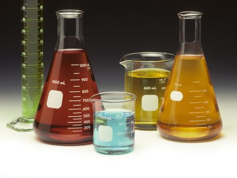 Scientific glassware filled with colored liquids on a graduated background