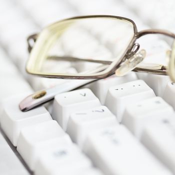 Spectacles lie on the surface of the keyboard