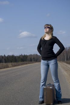 Beautiful country girl waiting on the road with her baggage