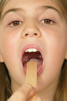 Young female child opening her mouth so the Doctor can examine her throat.
