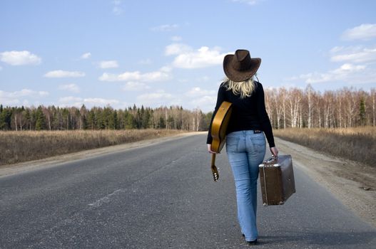 country girl with guitar goes on road solitary under sky