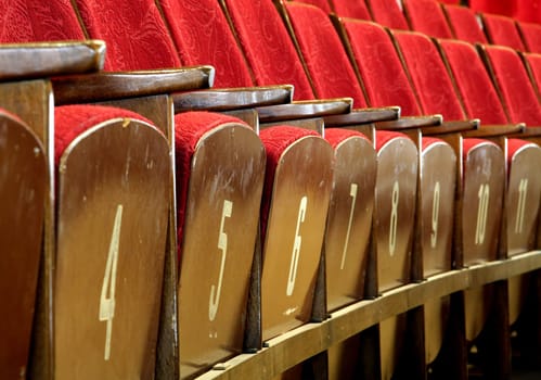 red wooden seats in theatre, numbers on seats
