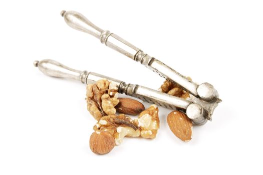 Assorted mixed nuts with a silver nutcracker on a reflective white background