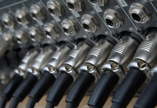 several jacks and empty jack holes on audio mixing machine, distance blur