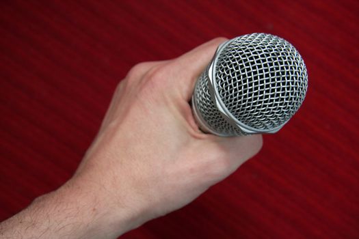 steel microphone in man hand, red background