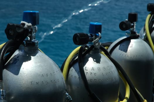 grey diving tanks on a boat, water in background