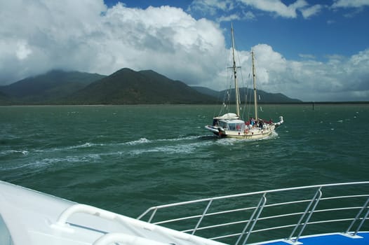 white cruising in green water, island in background, photo taken from yacht
