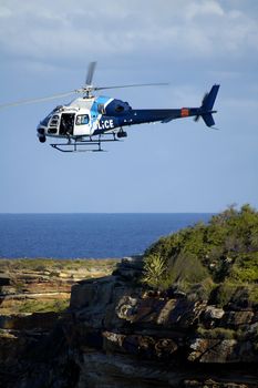 police helicopter flying above rocks on Sydney coastline