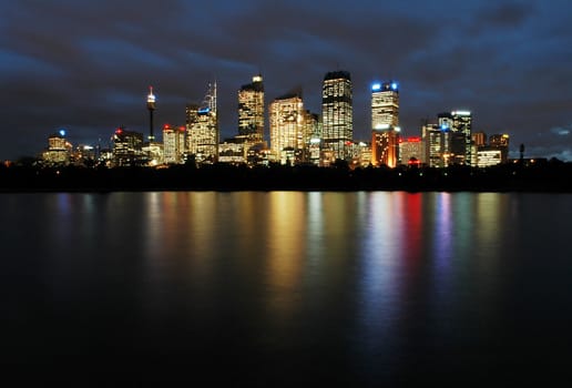 sydney cbd panorama at night, buildings reflection in water, dark cloudy night sky