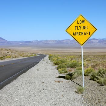 Low flying aircraft sign alongside desloate highway.