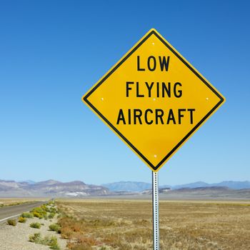 Low flying aircraft sign alongside desloate highway.