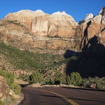 Two lane road winding through rocky desert cliffs in Zion National Park, Utah.