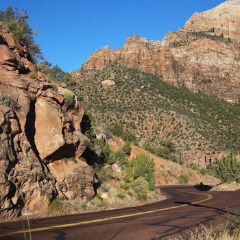 Two lane road winding through rocky desert cliffs in Zion National Park, Utah.