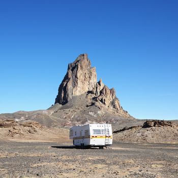 RV travelling toward rock formation in the desert of Monument Valley, Utah.