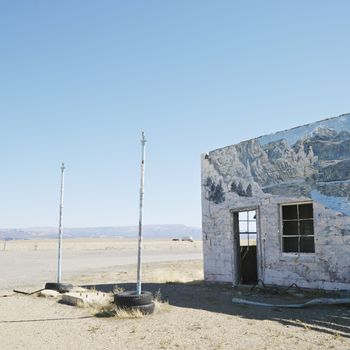 Building in barren desert landscape with winter scene mural painted on side.