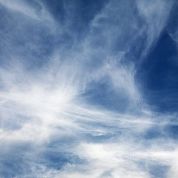 Wispy cloud formations against clear blue sky.