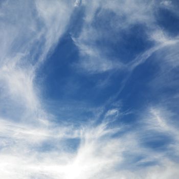 Wispy cloud formations against clear blue sky.