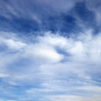 Wispy cloud formations against clear blue sky.