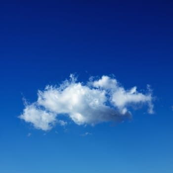 Lone puffy cumulus cloud in blue sky.