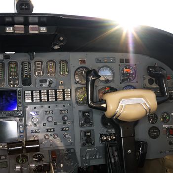 Interior shot of a airplane with the sun peeking over dashboard.