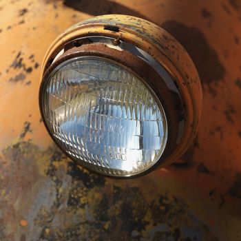 Close-up of headlight of scratched up rusty old pick-up truck.