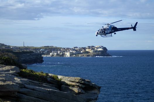 police helicopter flying above rocky coastline, photo taken in Sydney