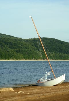 white small boat stranded on sand coast